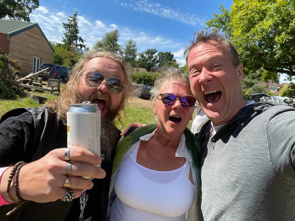 Three friends smiling together in the sun at Hoodstock
